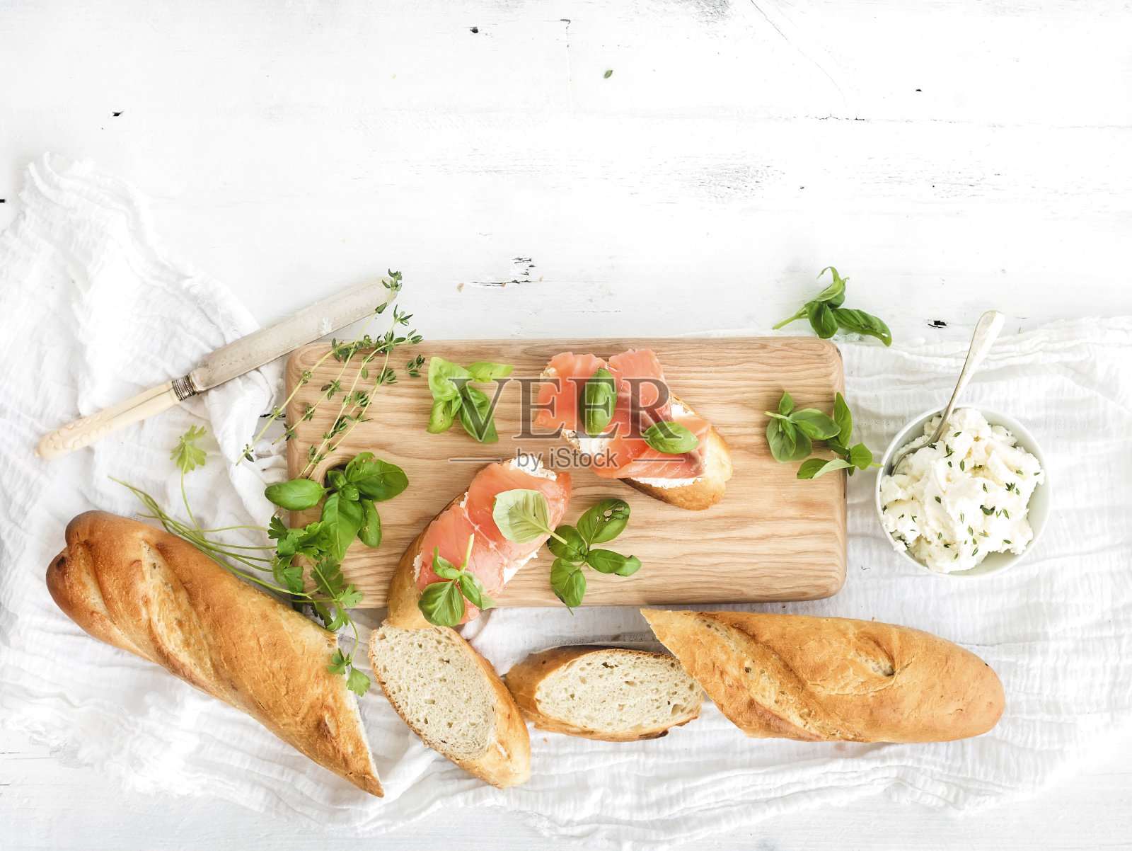 三文鱼、意大利乳清干酪和罗勒三明治配法式长棍面包放在质朴的木板上照片摄影图片