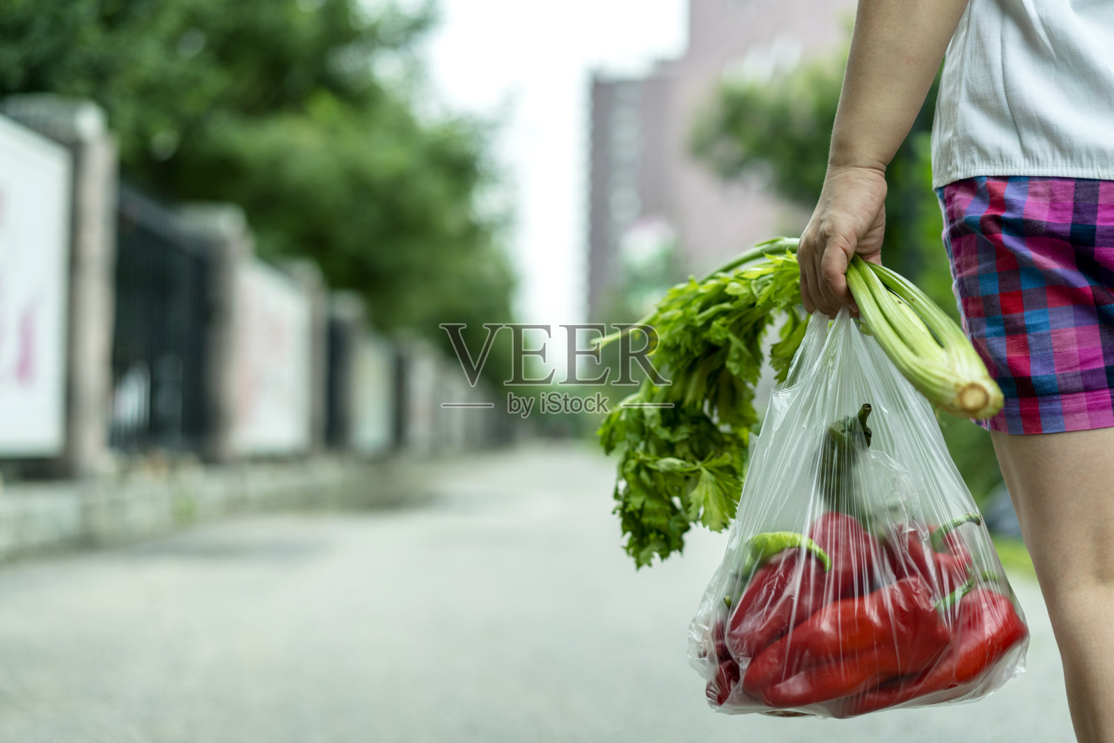 一个女人带着一袋蔬菜走在路上照片摄影图片