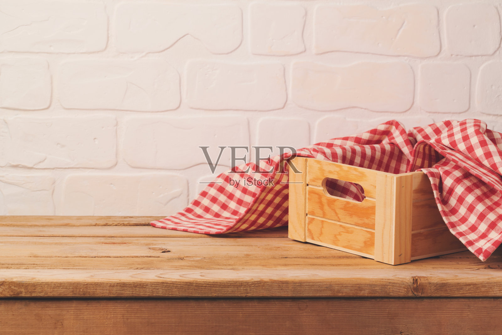 砖墙背景上是空的木制甲板桌，上面有盒子和桌布照片摄影图片