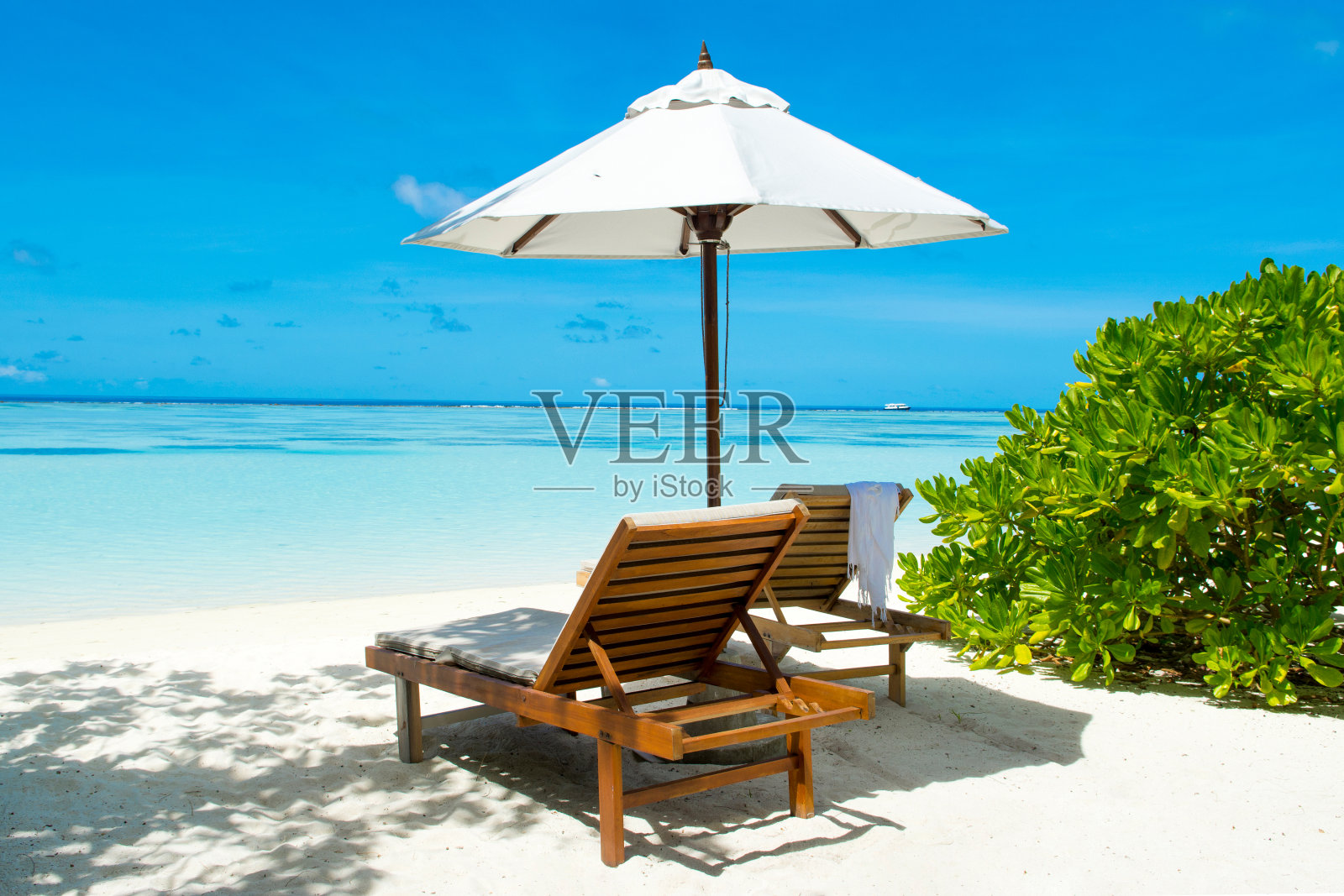 马尔代夫岛的沙滩上有日光浴床和遮阳伞，风景优美照片摄影图片