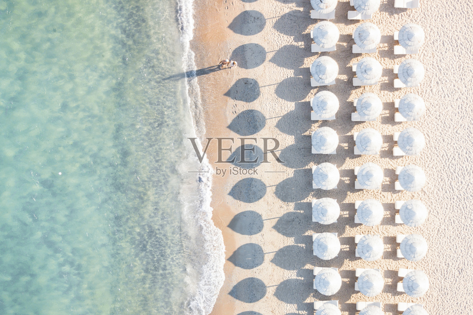 鸟瞰图惊人的海滩与白色伞和蓝绿色的海在日落。地中海，撒丁岛，意大利。照片摄影图片