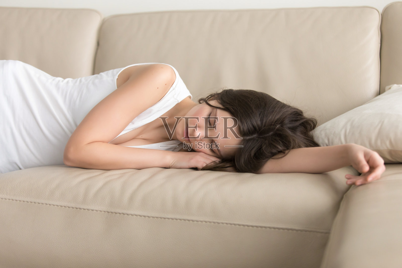 年轻女子躺在沙发上睡觉，在家里打盹照片摄影图片