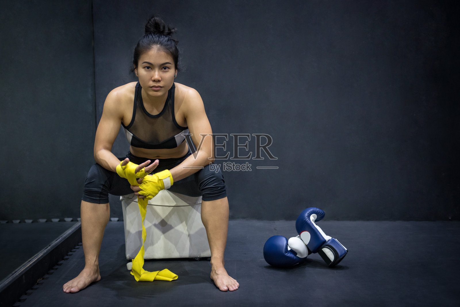 手腕上戴着黄色带子的亚洲女拳击手，看到拳击手套在地板上照片摄影图片