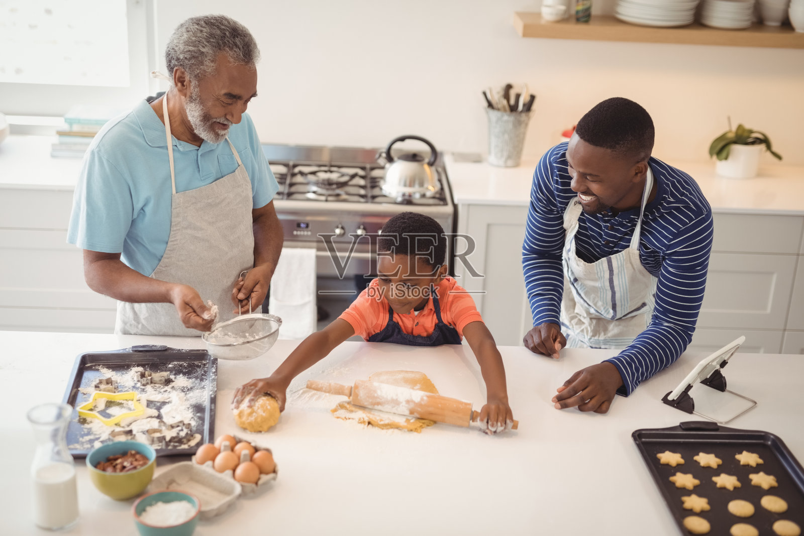 男孩和他的父亲和祖父在厨房里准备饼干面团照片摄影图片