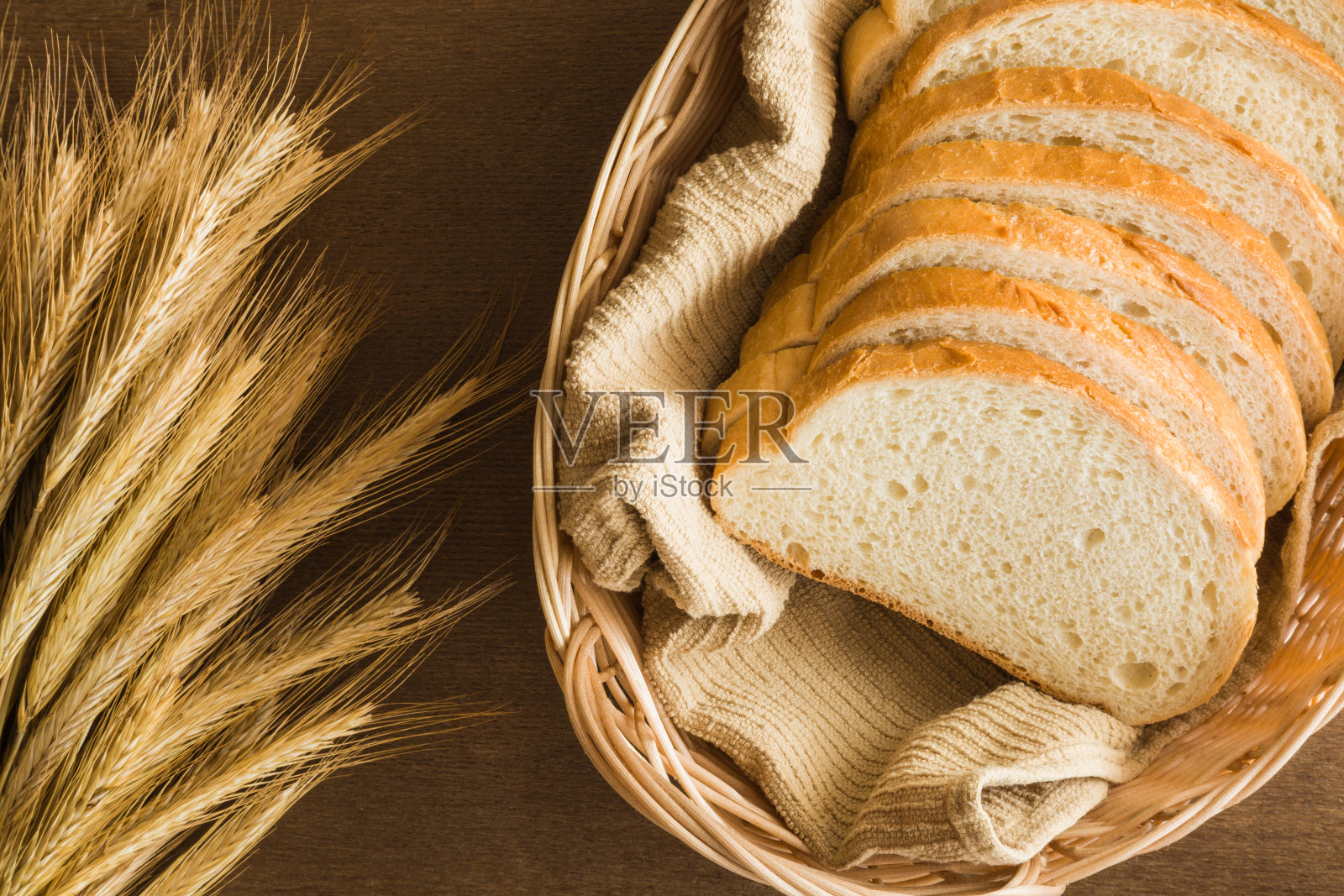 厨房木桌上的篮子里放着新鲜的白面包片。乡村的气氛。健康的饮食和生活方式。食品的背景。照片摄影图片
