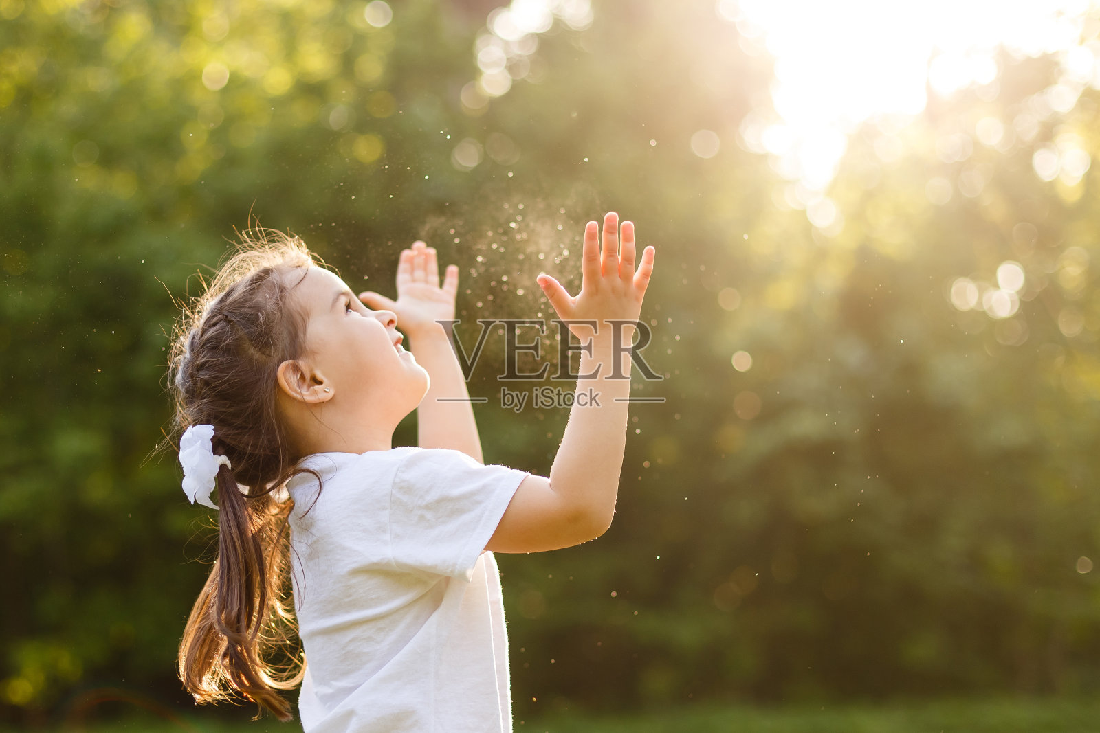 可爱的小女孩，有着快乐的乐趣和开朗的笑脸。无忧无虑的孩子在绿色的夏日草地上奔跑跳跃，抓着肥皂泡。幸福、童年和自由的概念。照片摄影图片