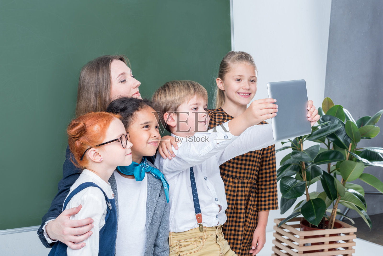 年轻女老师和可爱的小学生在课堂上用平板电脑自拍照片摄影图片