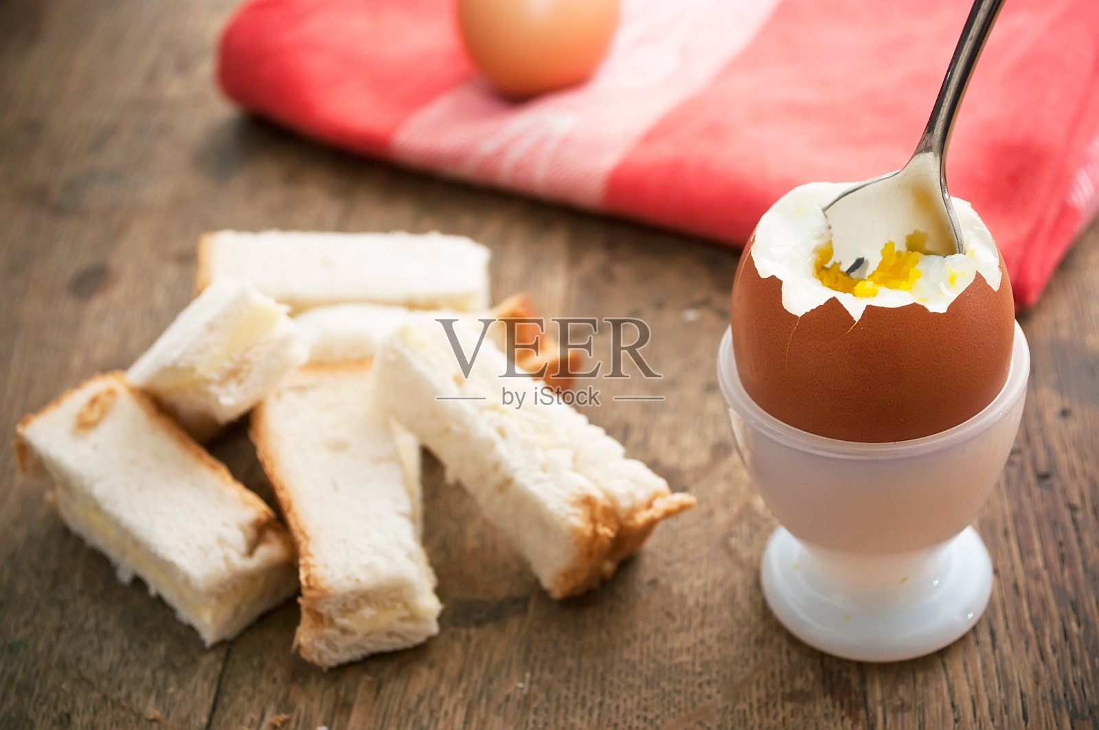 半熟的煮蛋在蛋杯和吐司手指在木桌上照片摄影图片