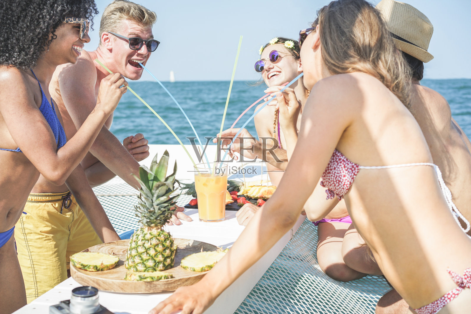 快乐的朋友喝热带鸡尾酒和吃菠萝水果在船派对-年轻人有乐趣的暑假-青年，旅游和假日概念-主要集中在金发男人照片摄影图片
