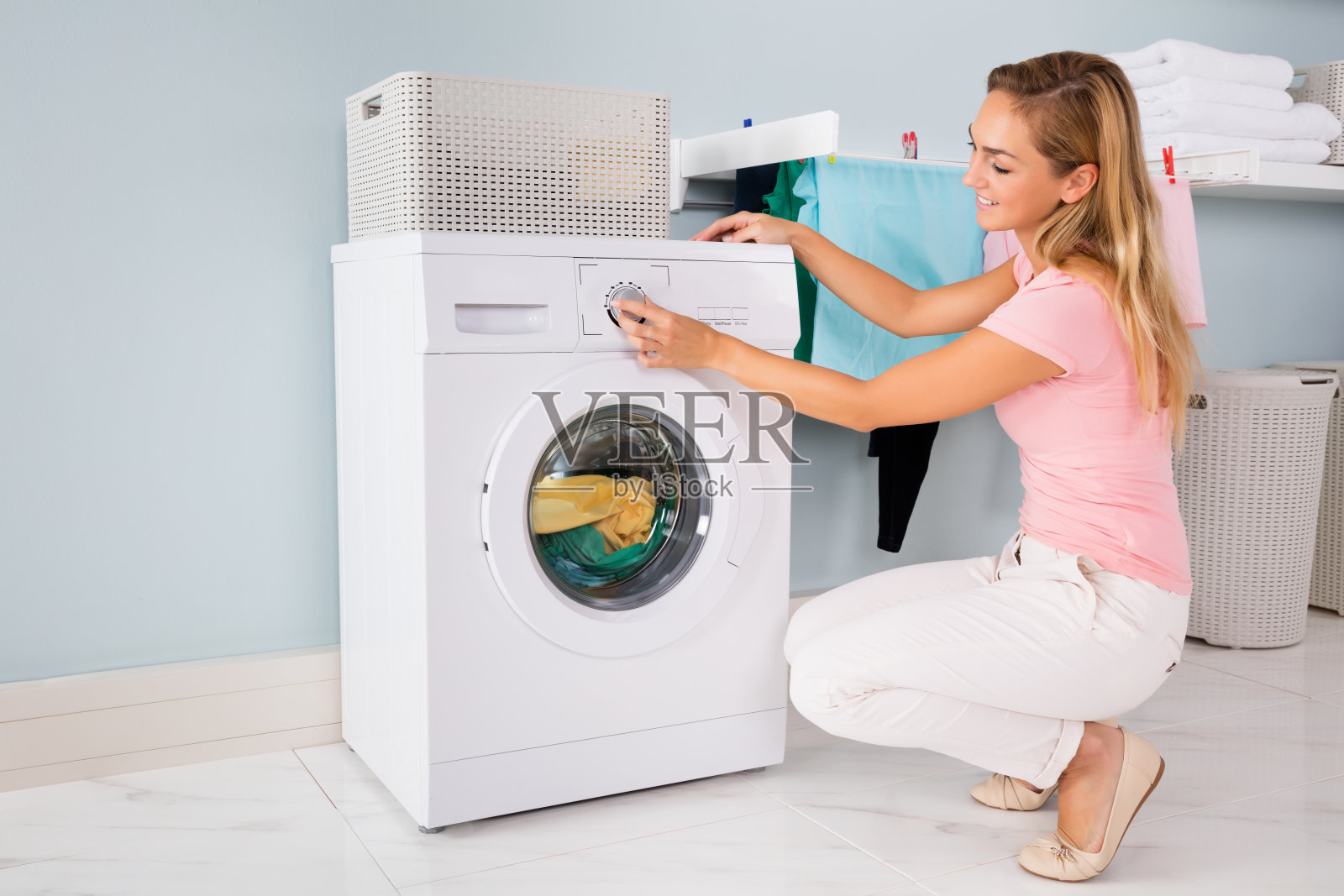 在杂物间用洗衣机的女人照片摄影图片