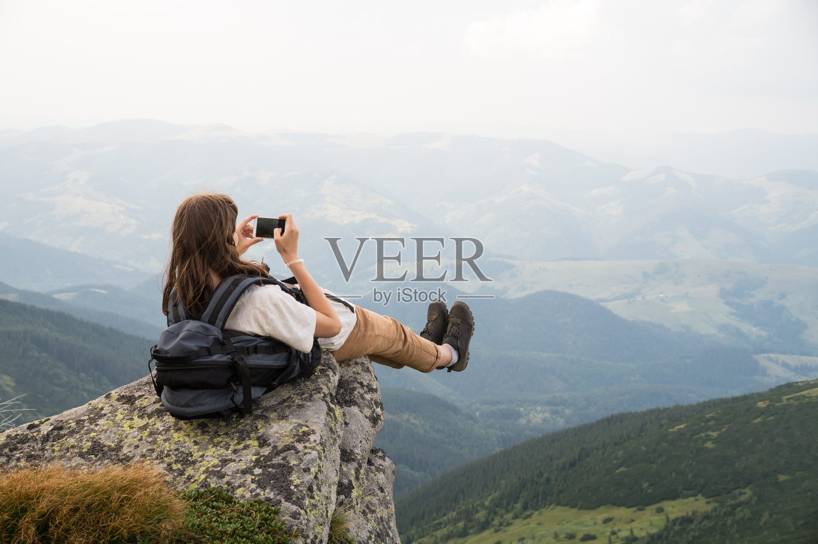 一名女游客在悬崖顶上用手机拍照照片摄影图片
