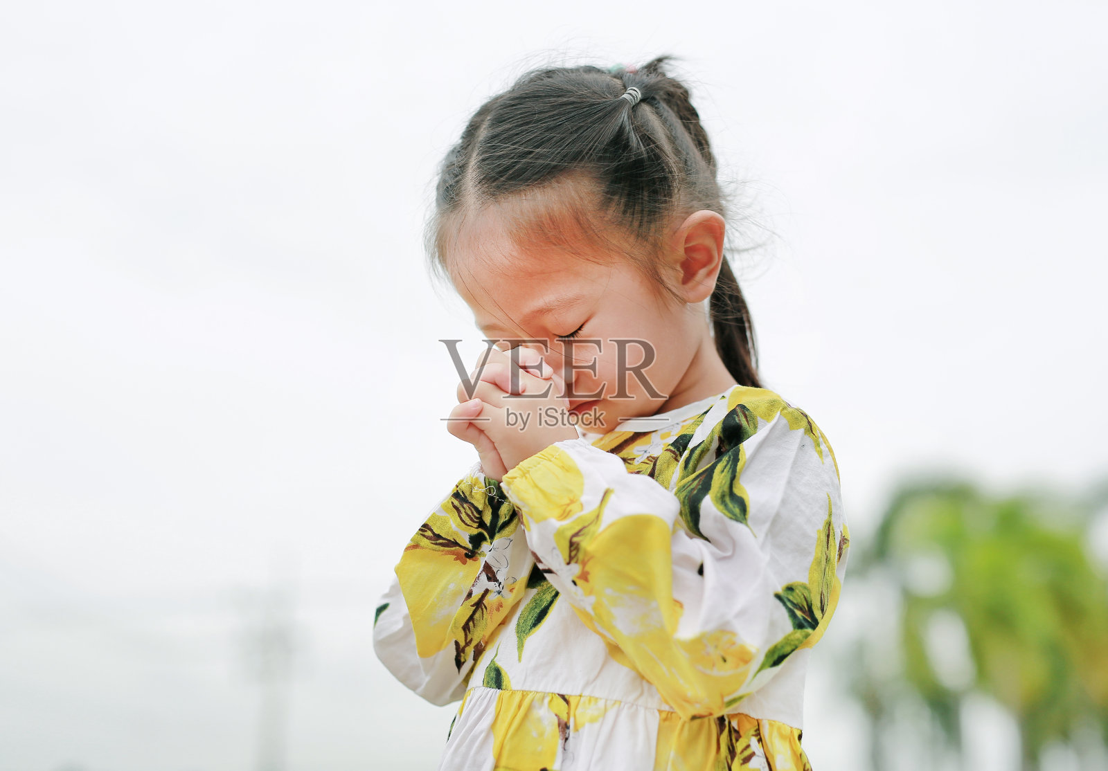 可爱的小女孩在室外花园祈祷。精神性和宗教观念。照片摄影图片