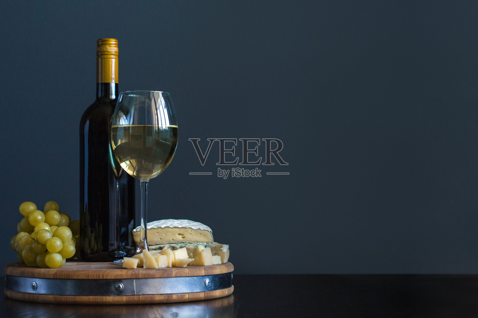 瓶子和玻璃杯与白葡萄酒靠近奶酪组成在木板上照片摄影图片