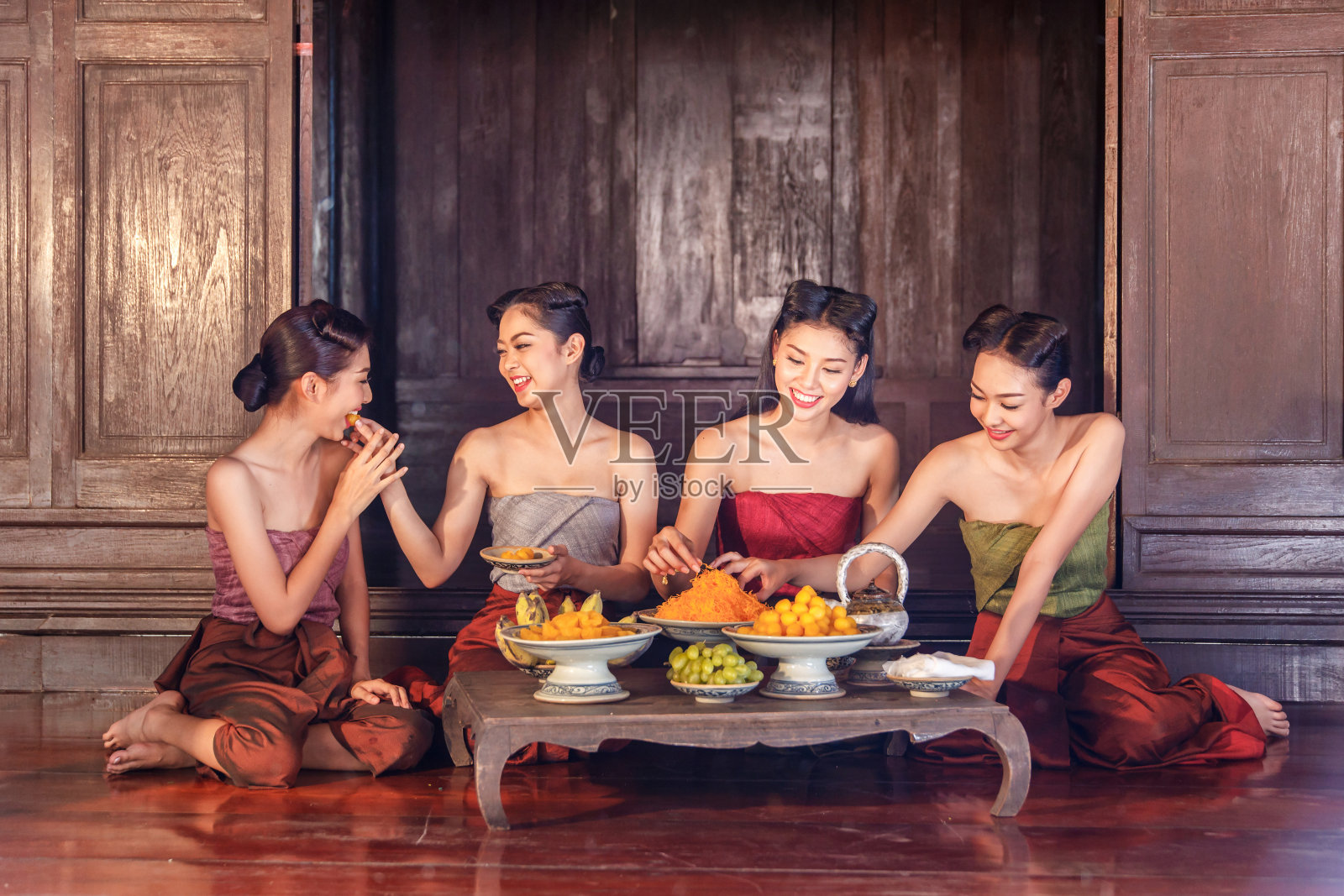美丽的泰国女孩穿着泰国传统服装，喜欢吃泰国甜点照片摄影图片