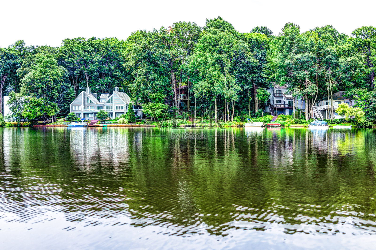 奥杜邦湖，在雷斯顿，弗吉尼亚州的湖畔滨水房屋与夏季的绿色树叶在树上的反射照片摄影图片