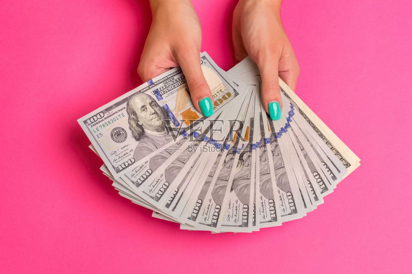 一个女人手里拿着钱。粉红色的背景。俯视图拷贝空间照片摄影图片