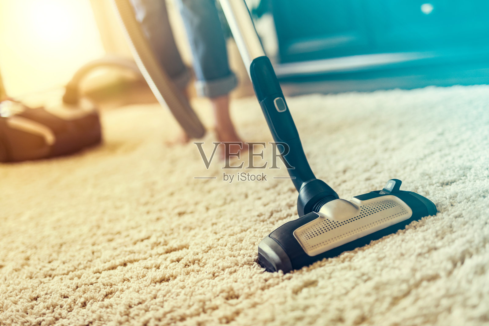 用吸尘器清扫屋子里地毯的女人。照片摄影图片