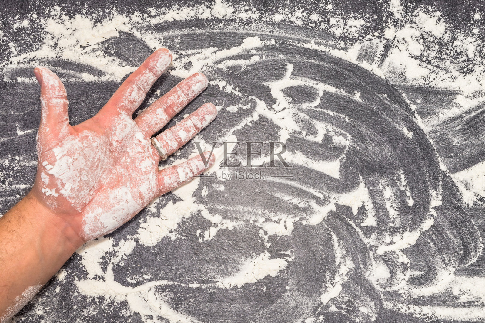 小麦粉在灰色的工作面上，男性的手照片摄影图片