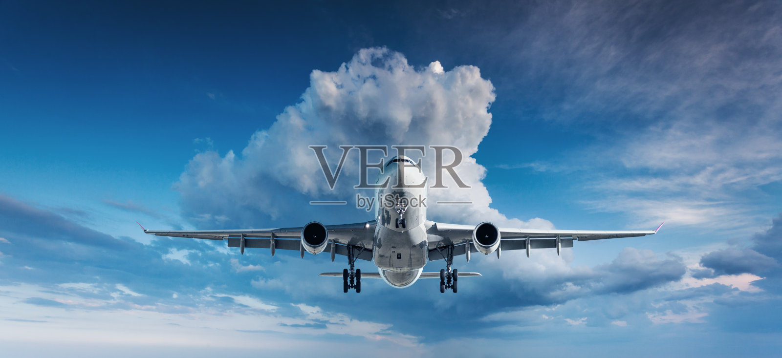 美丽的飞机。一架白色的客机在阴天带着云的蓝天中飞翔。旅游的背景。客运班机。商务旅行。商用飞机。飞机照片摄影图片