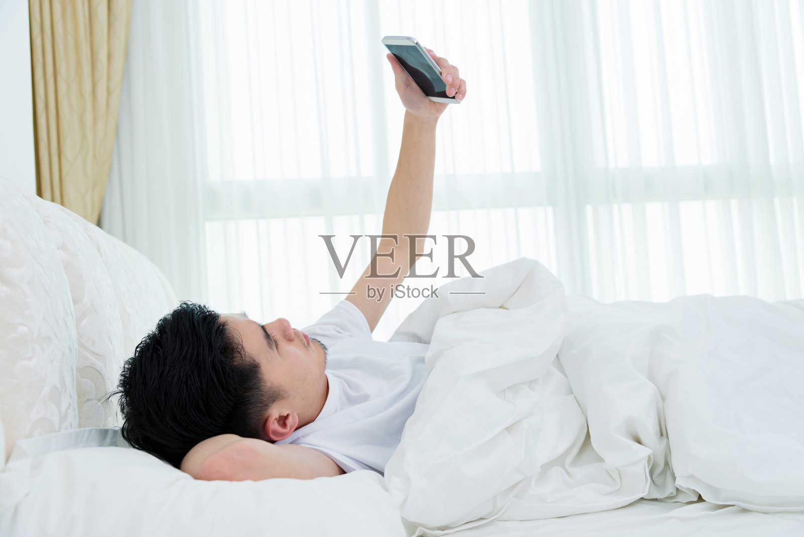 年轻人在床上使用智能手机照片摄影图片