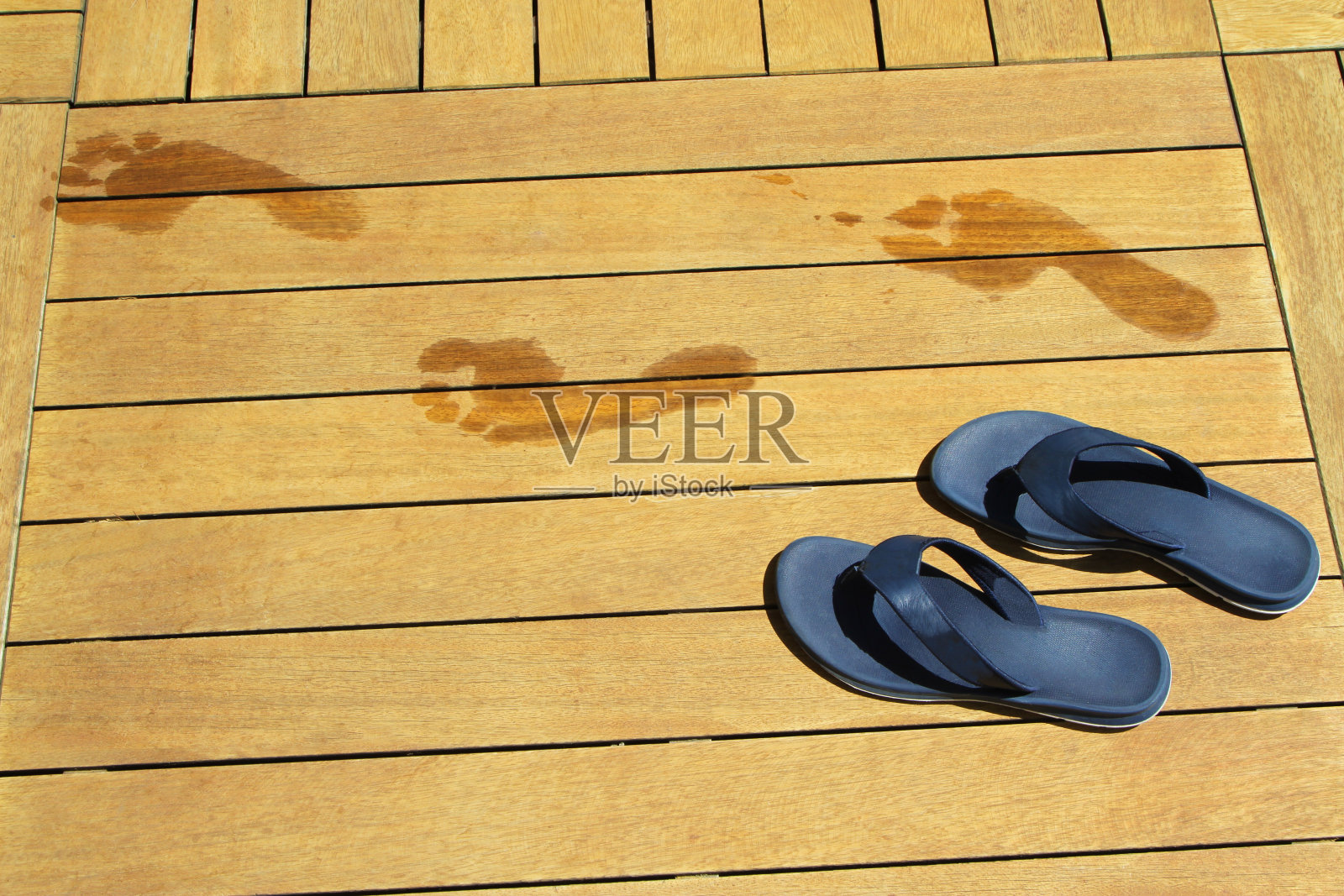 人字拖和水池边木板上的湿脚印。照片摄影图片