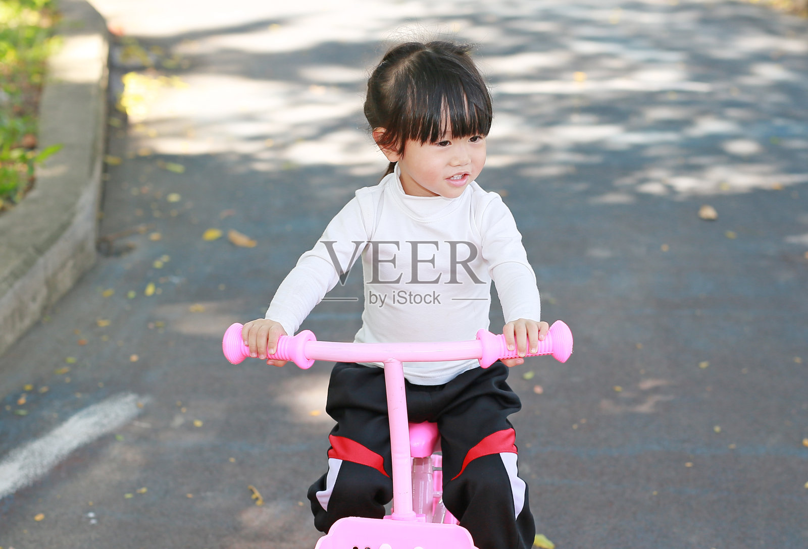 一个亚洲小女孩在公园里骑自行车。照片摄影图片