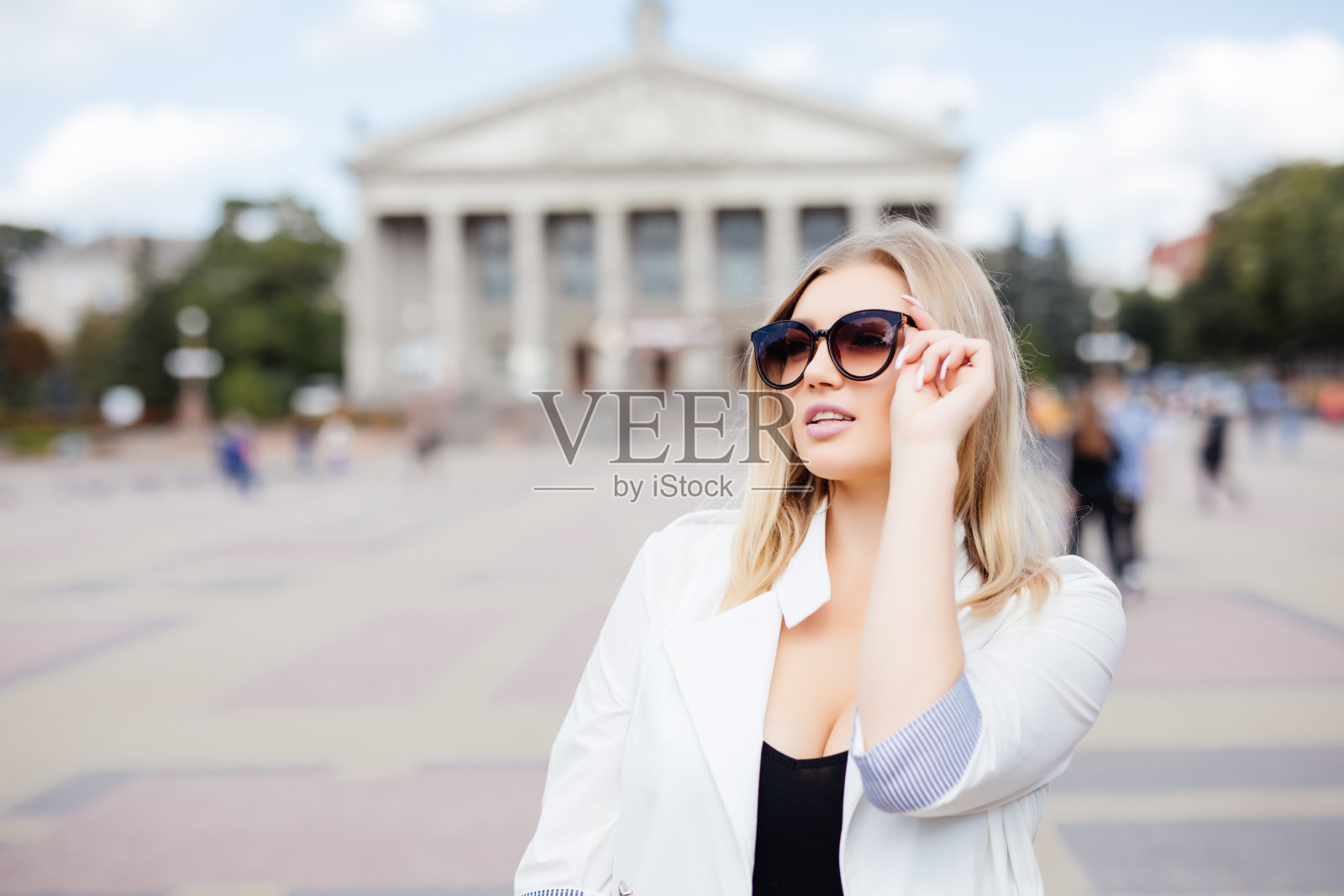 年轻漂亮的女孩戴着时髦的太阳镜在城市的街道上。照片摄影图片