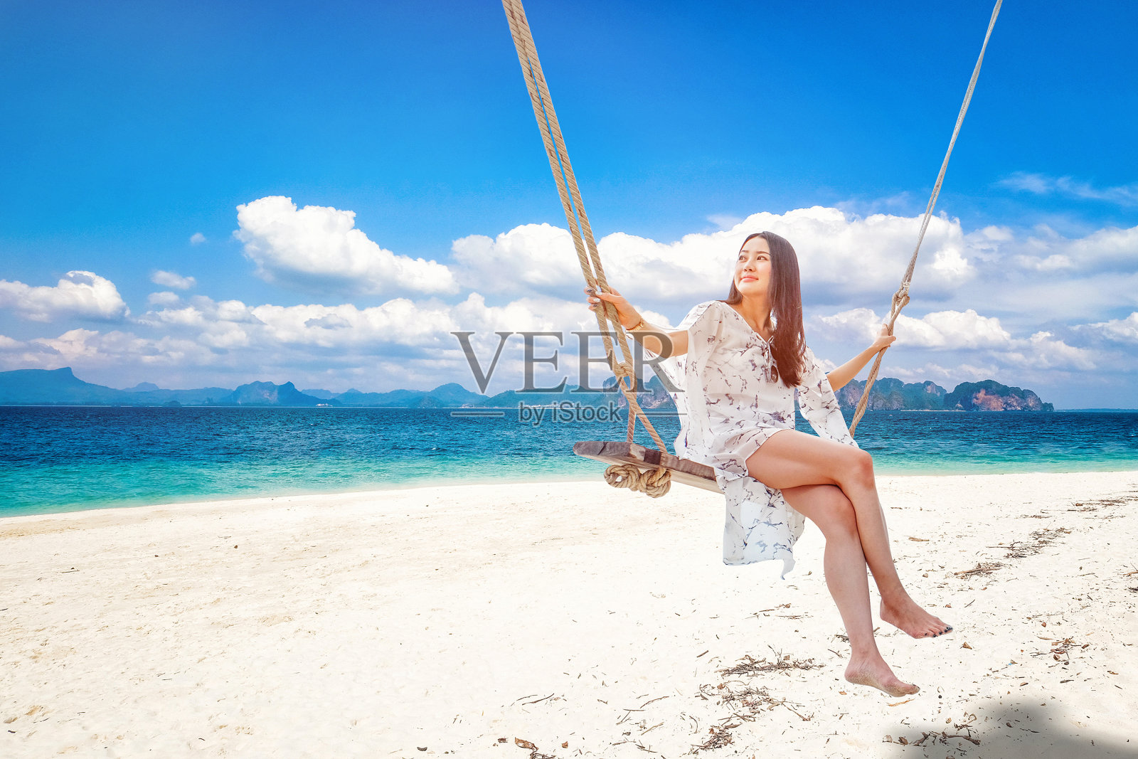 泰国甲米海滩上的美女坐在秋千上照片摄影图片