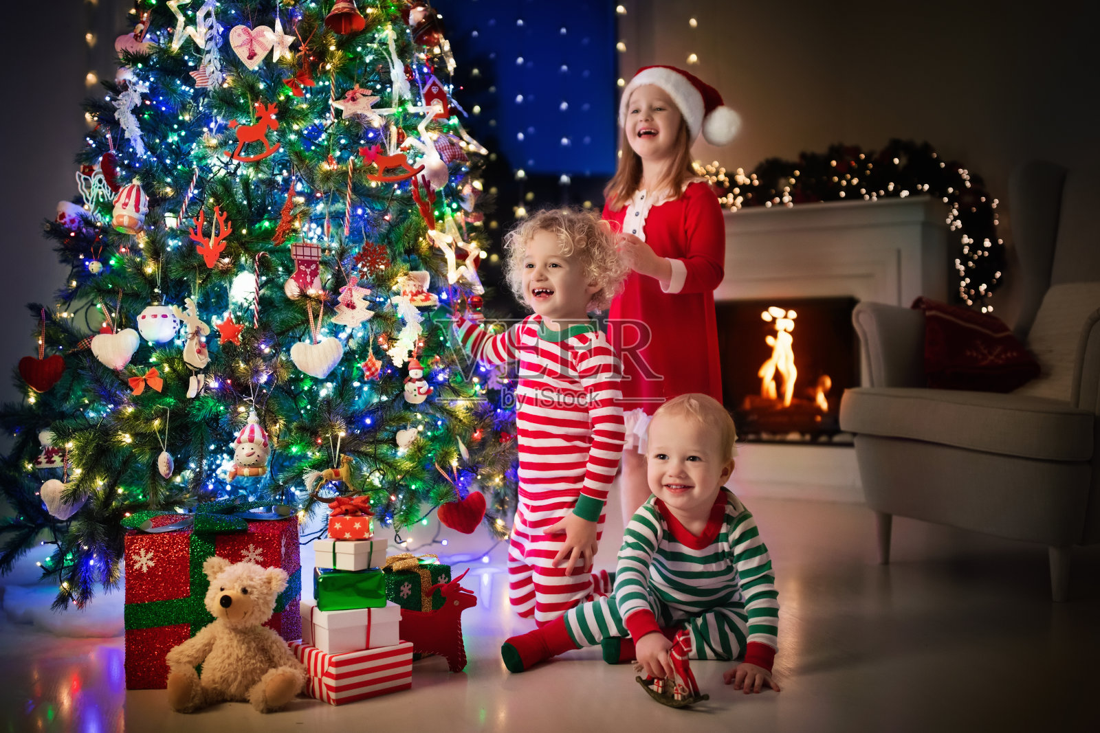 孩子们在圣诞树上。圣诞夜壁炉旁的孩子们照片摄影图片
