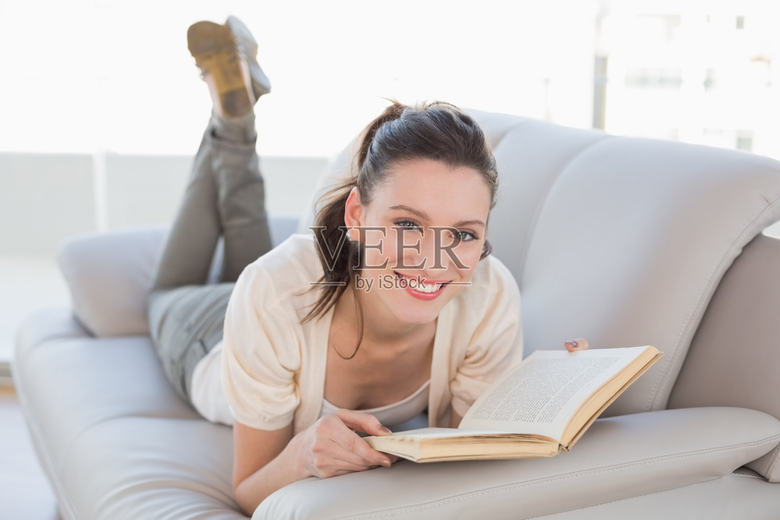 一个随意的女人在沙发上看书照片摄影图片