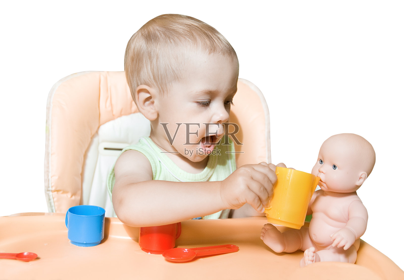 婴儿玩娃娃，孩子喂玩具，孩子坐在桌子前，白色孤立照片摄影图片