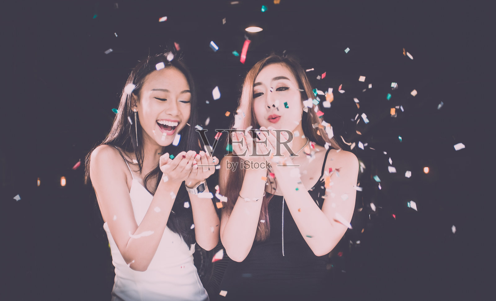 两个亚洲女人的愉快的朋友有一个聚会上的乐趣。假日,庆祝。在黑色背景照片摄影图片