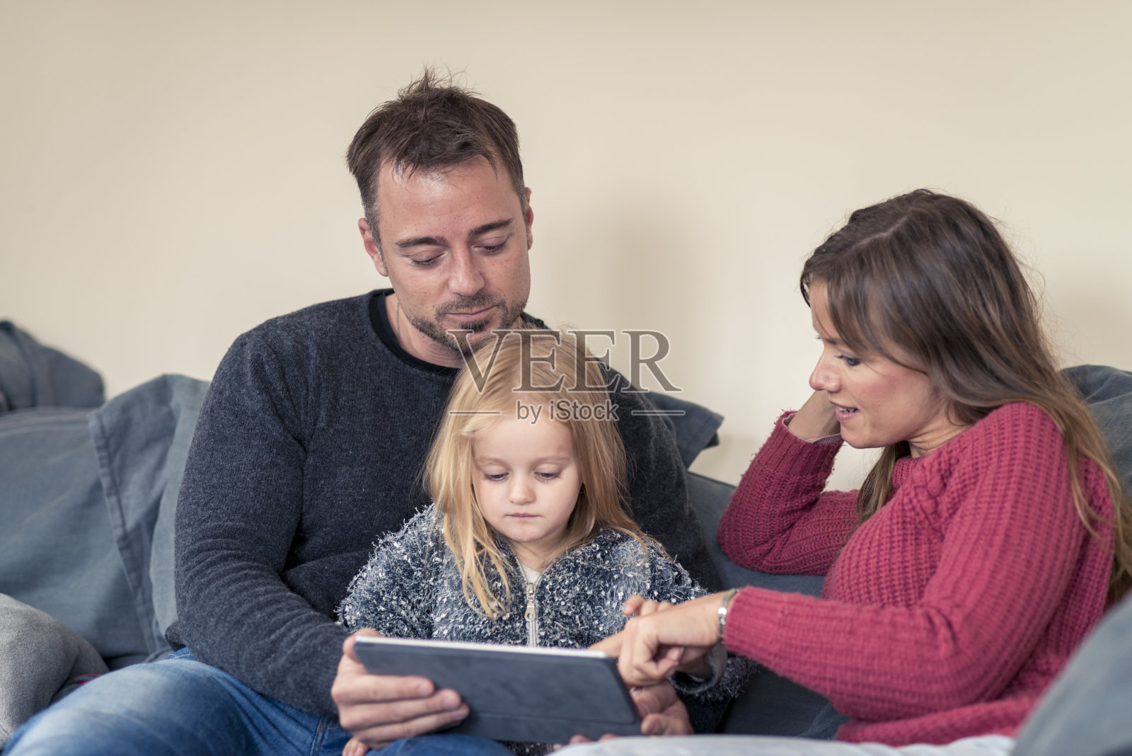 年轻的父母和女儿在看数字平板电脑照片摄影图片