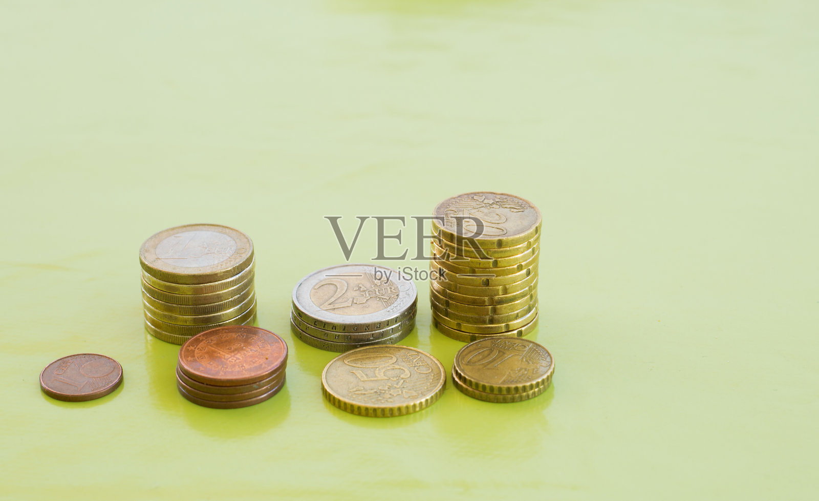 绿色桌子上随机数量的欧元硬币照片摄影图片