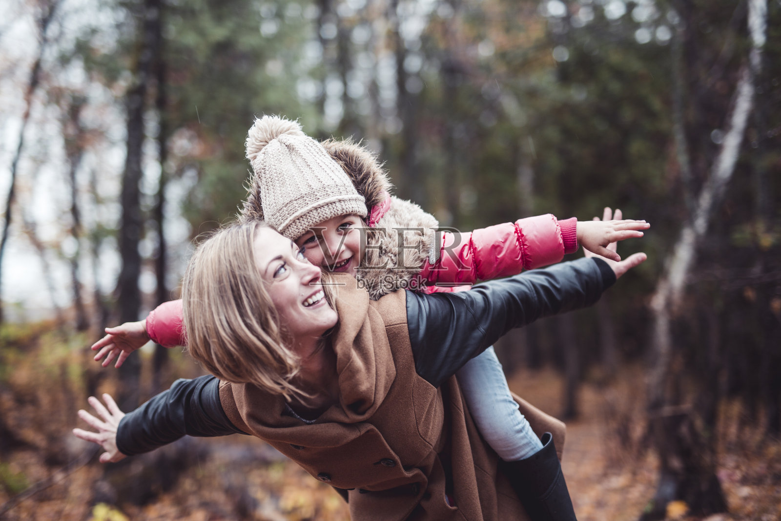一个微笑的年轻女人和一个小女孩在秋天的肖像照片摄影图片