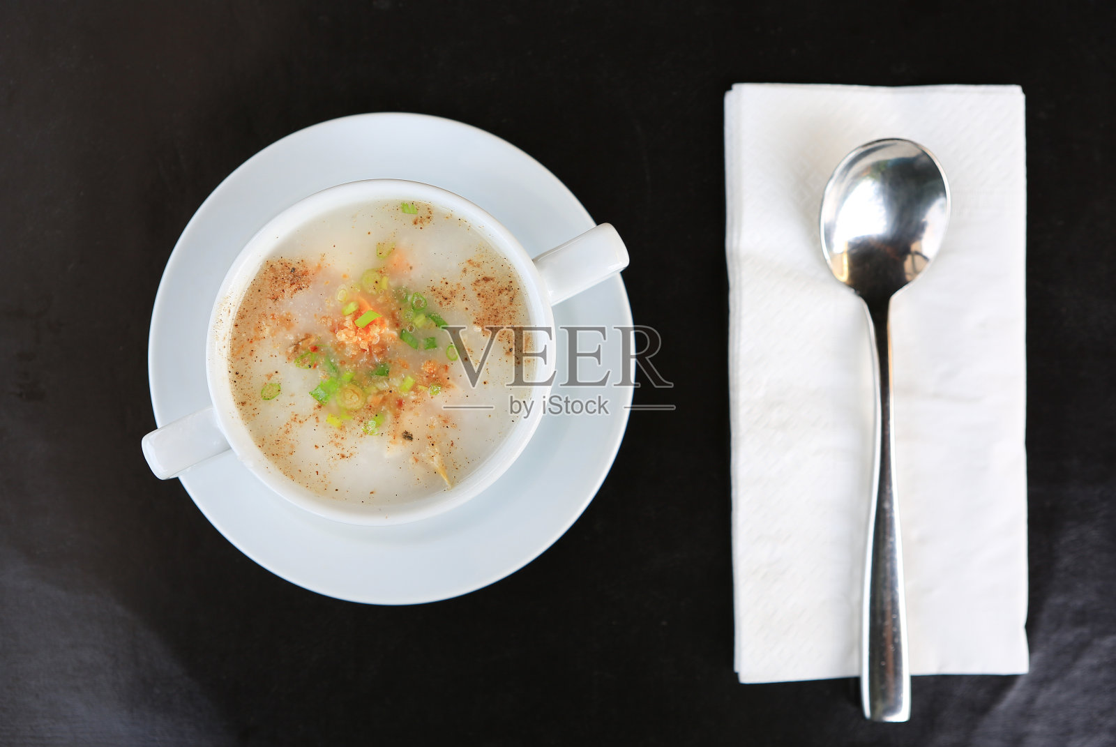 传统的泰国粥米粥在杯子与勺子和纸巾。前视图。照片摄影图片