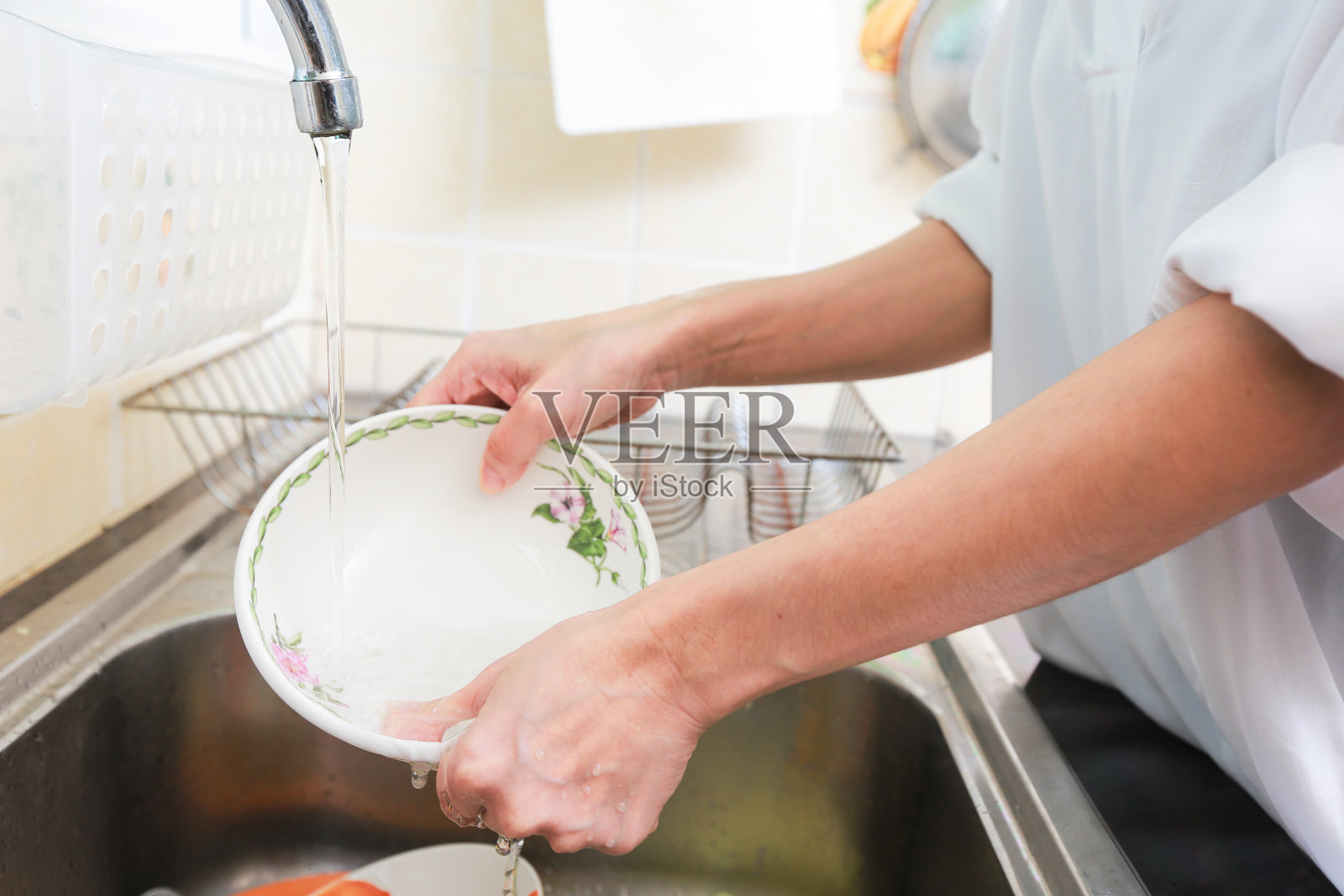 在厨房里洗碗的女人的双手。照片摄影图片