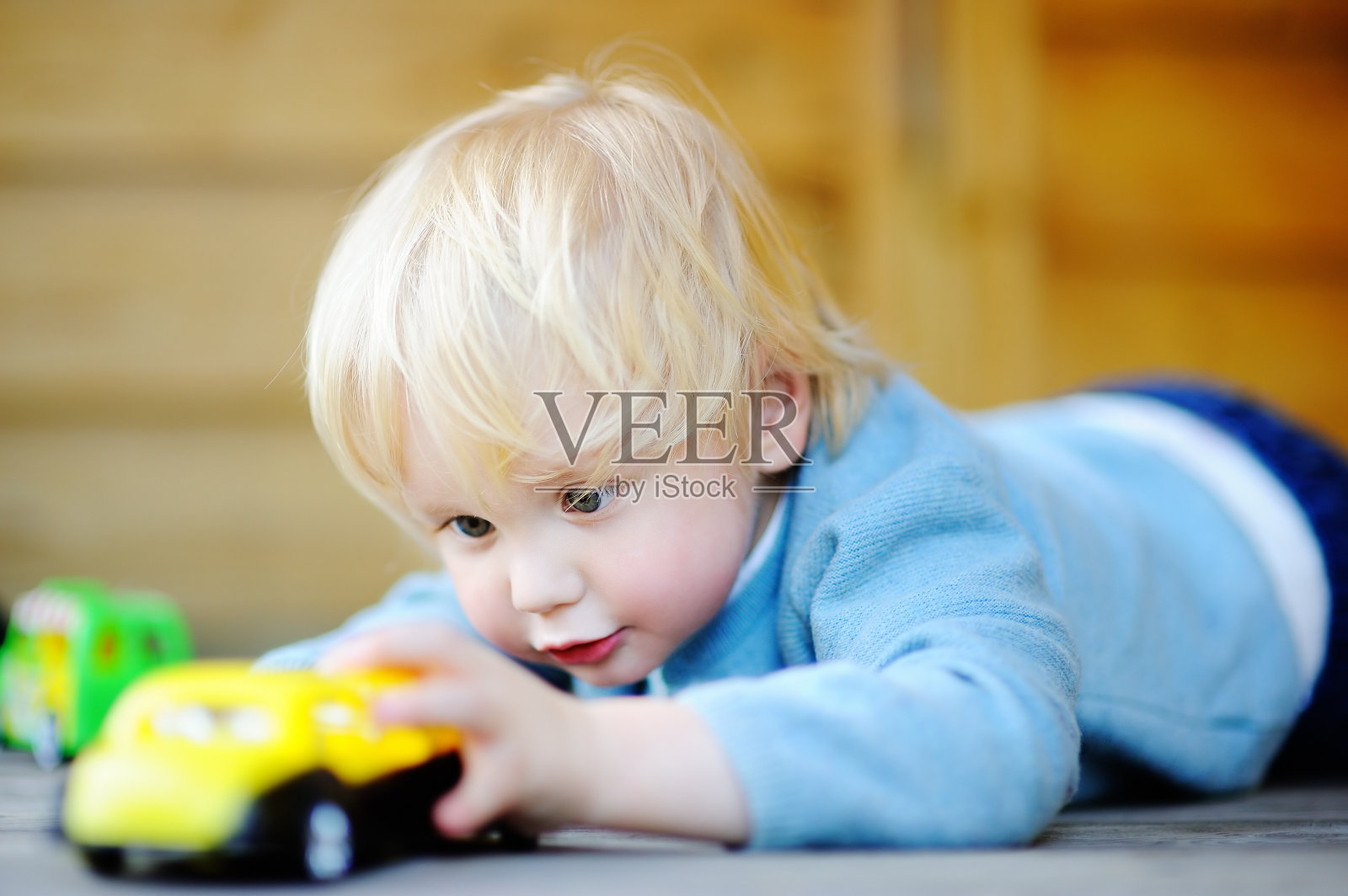 可爱的蹒跚学步的小男孩在玩玩具车照片摄影图片