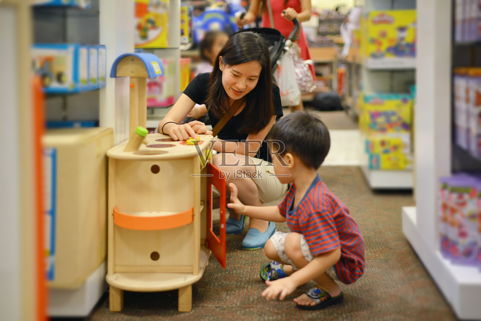 年轻的亚洲母亲和她的孩子在购物中心购物玩具照片摄影图片