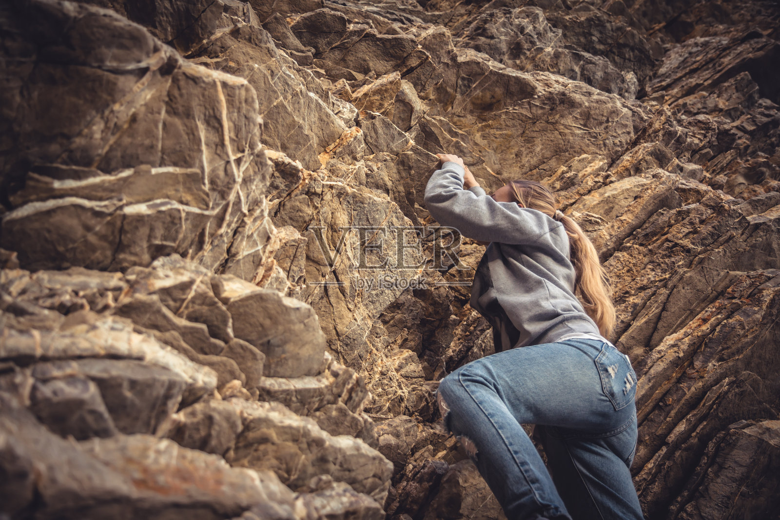 勇敢的女人爬上岩石实现她的目标照片摄影图片