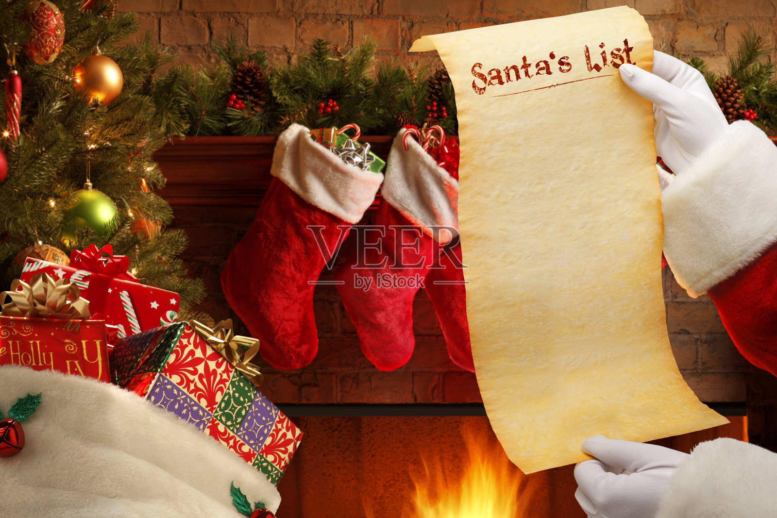 圣诞老人在圣诞树和壁炉前拿着空白名单照片摄影图片