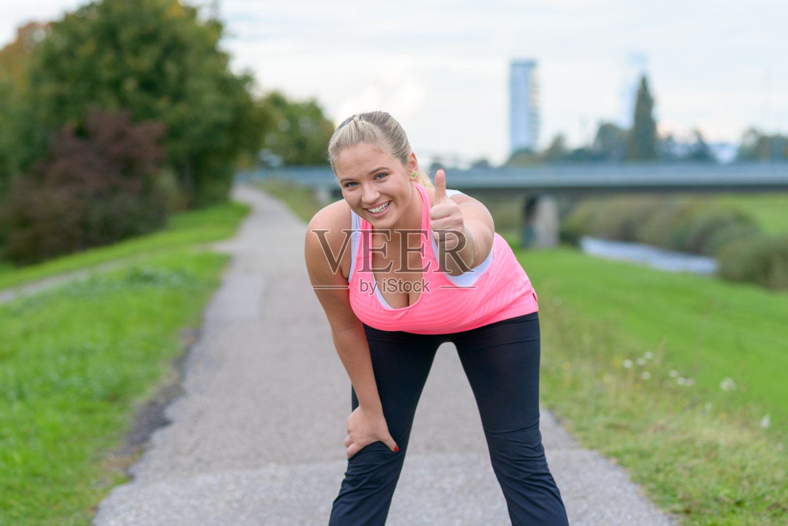 金发微笑的女人在跑步后竖起大拇指照片摄影图片