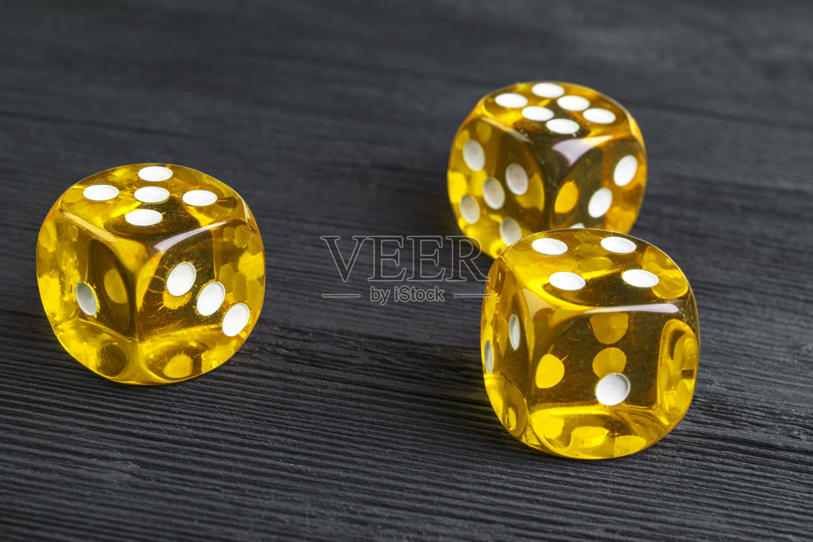 风险概念-玩骰子在黑色木制背景。用骰子玩游戏黄色的赌场骰子。滚动骰子的概念商业风险，机会，好运或赌博照片摄影图片
