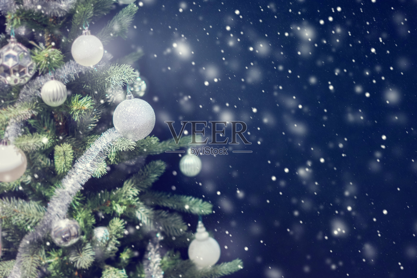 银色小玩意儿挂在圣诞树上的特写。设计模板素材