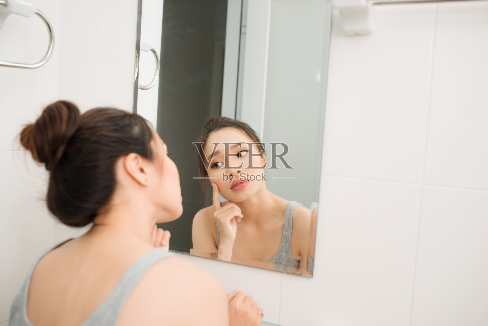 亚洲妇女拿着镜子，触摸和担心她的脸照片摄影图片