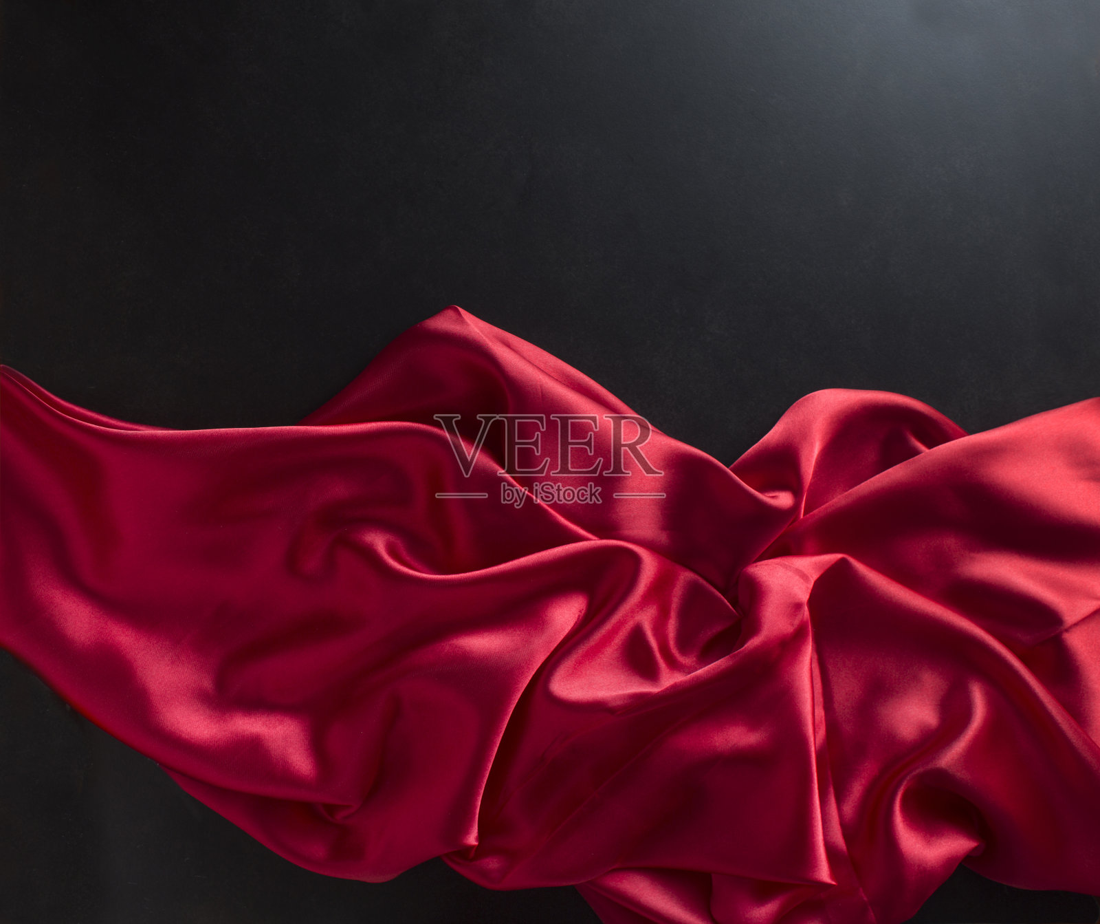 自由流动的红色缎子在黑色的背景。照片摄影图片