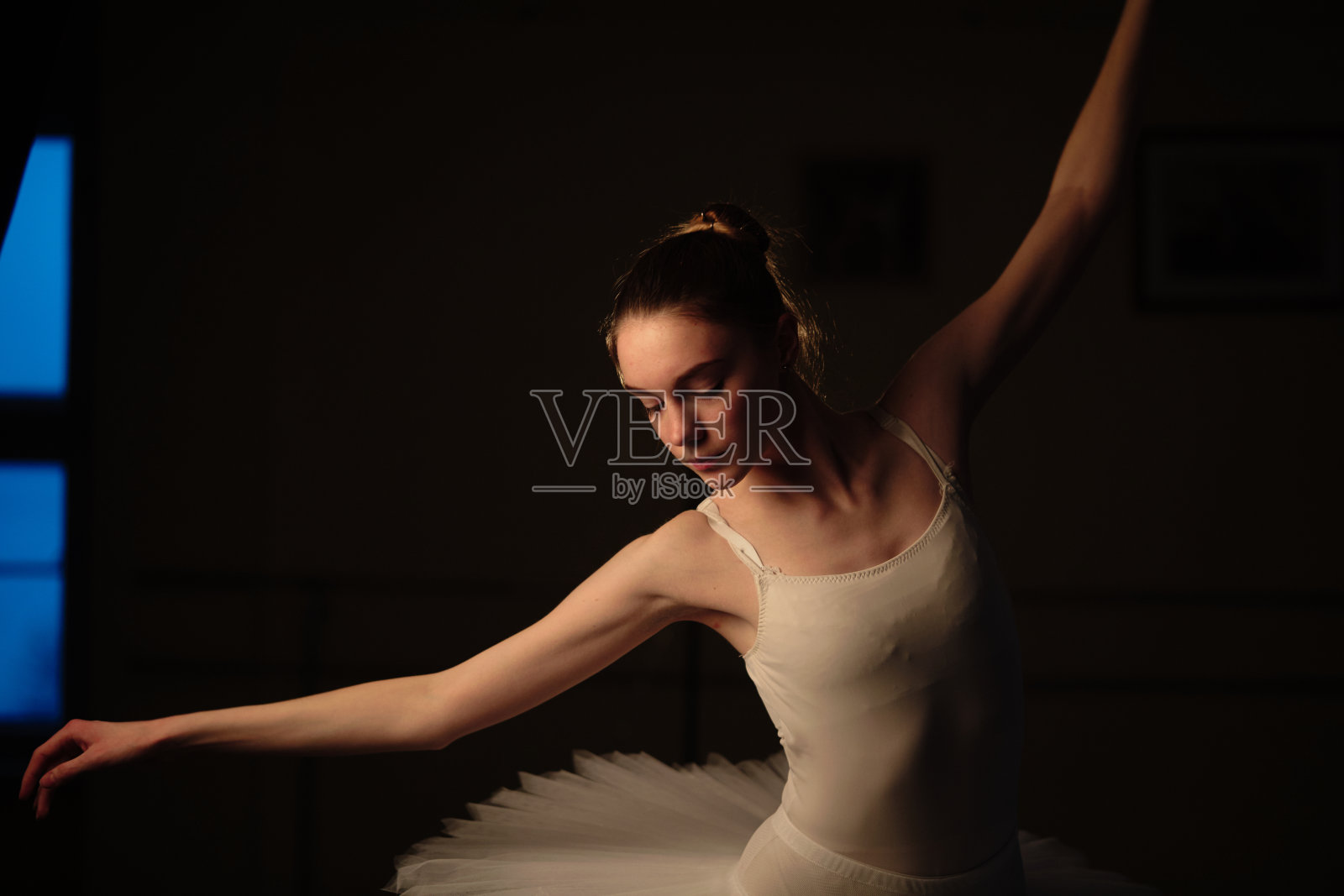 一位优雅的芭蕾舞演员在黑暗中以灯光为背景跳着芭蕾舞元素照片摄影图片