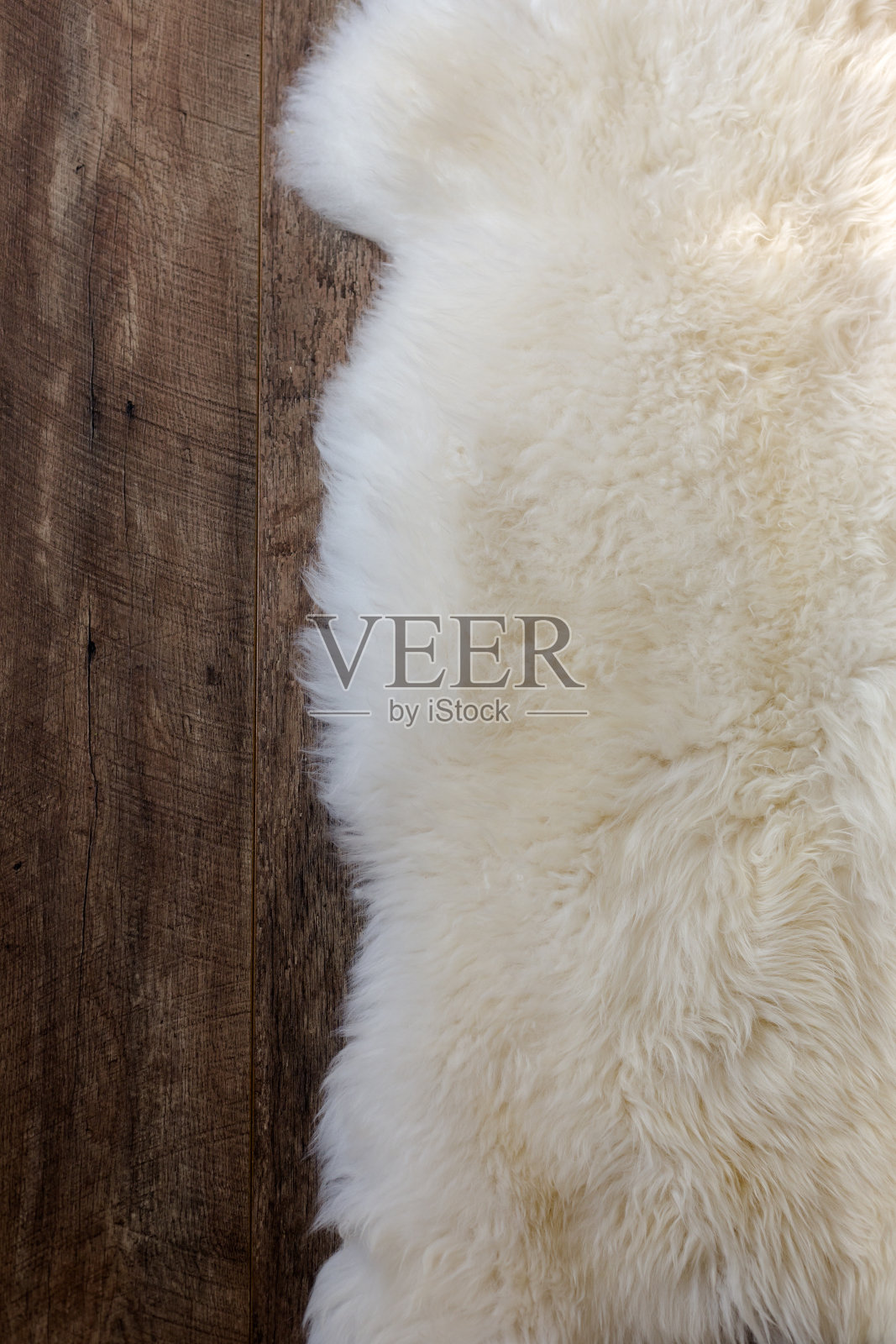 深色橡木地板上的天然羊皮毛绒毛皮地毯照片摄影图片