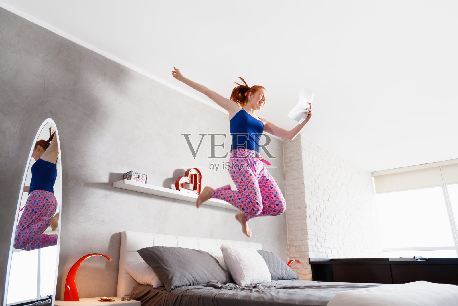 好消息是快乐的年轻女孩在床上跳照片摄影图片