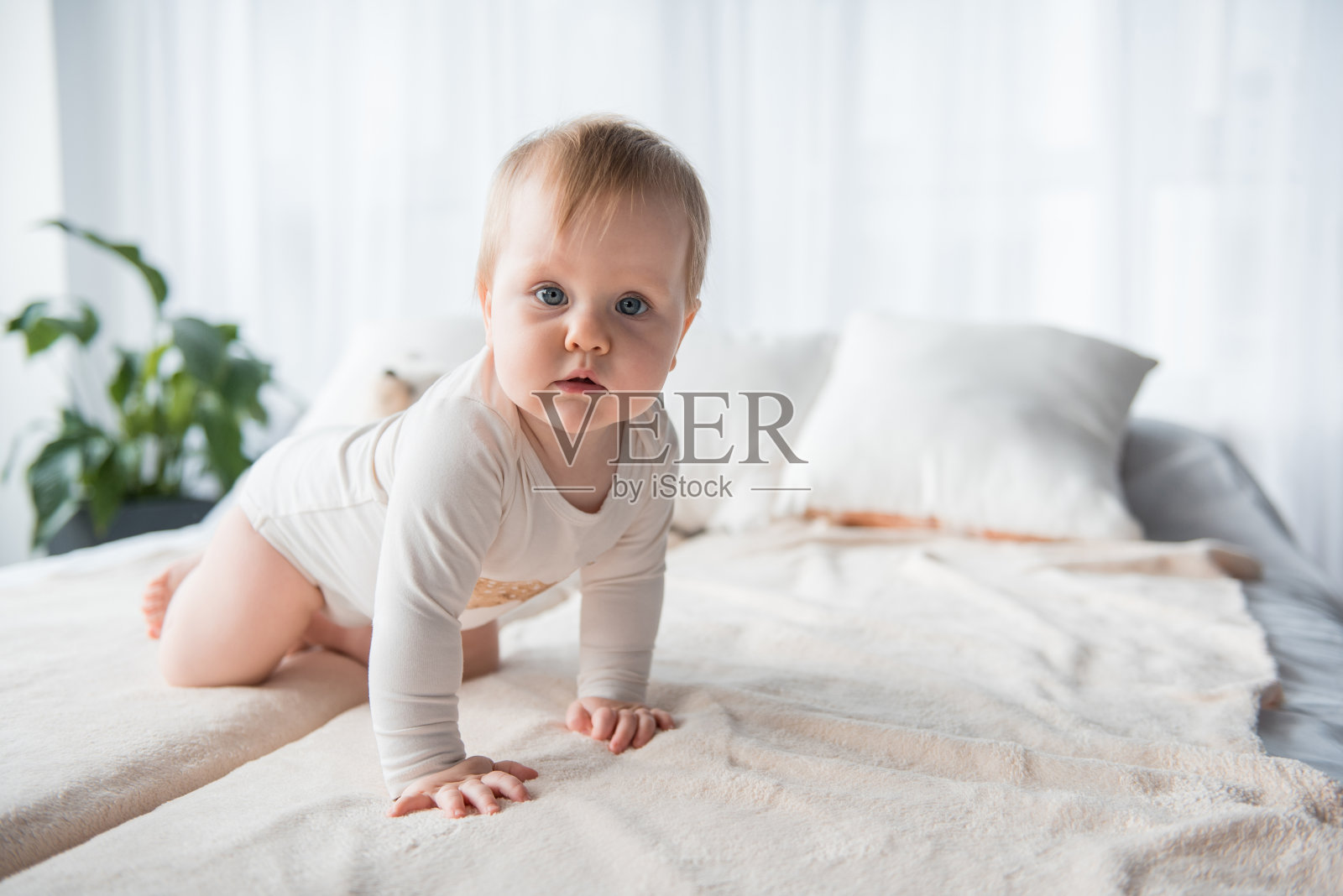 可爱的婴儿匍匐在床单上照片摄影图片